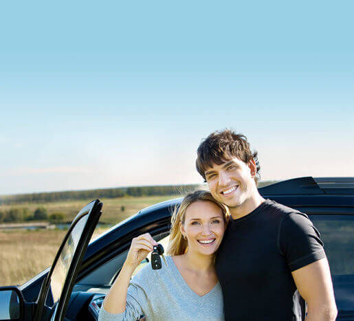 Happy couple holding the keys from a new used car
